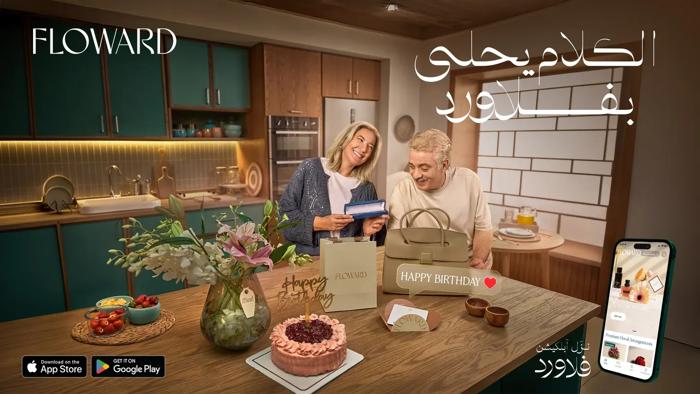 Floward birthday artwork with two women opening a card beside flowers and cake in a kitchen
