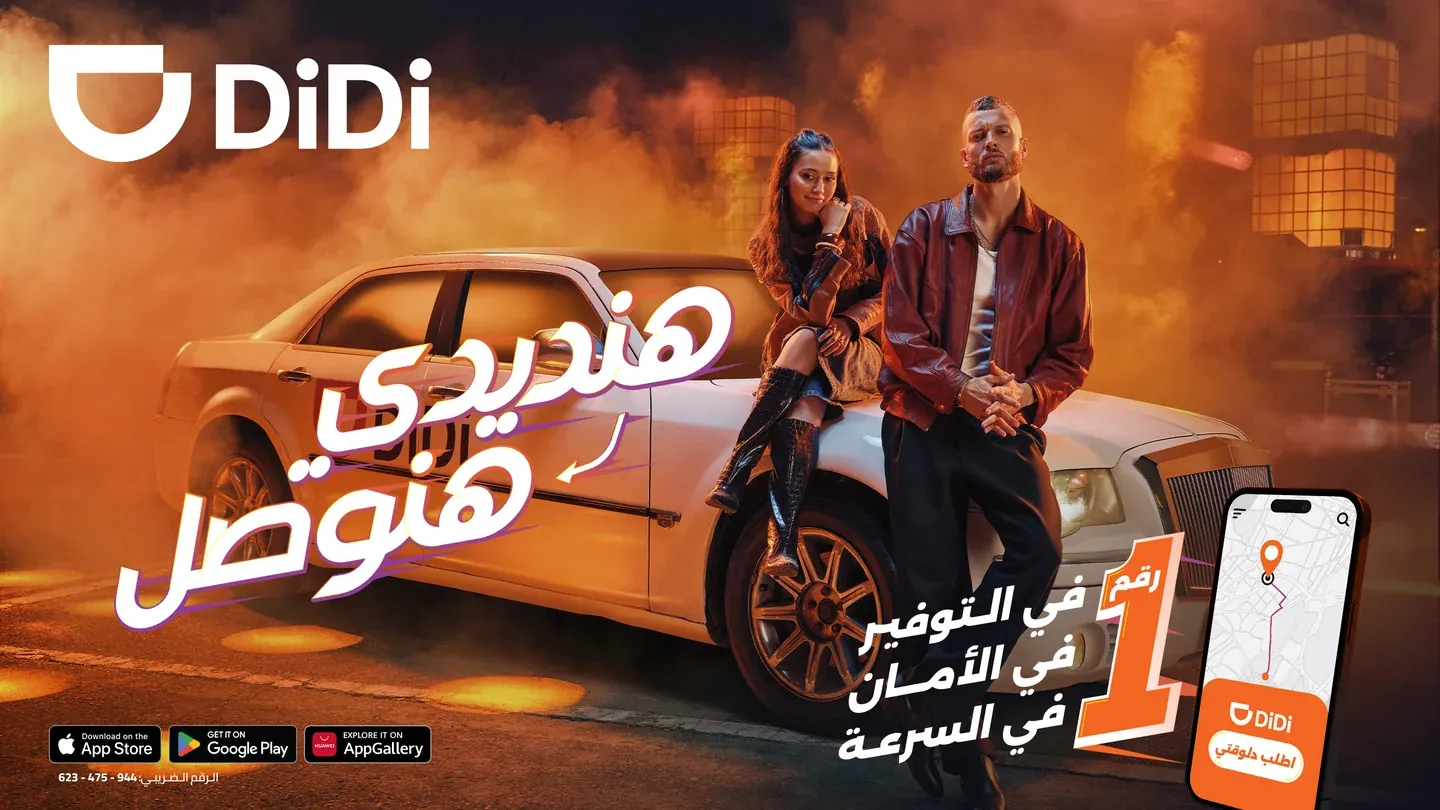 DiDi real campaign artwork with a man and woman beside a white car in orange-lit haze